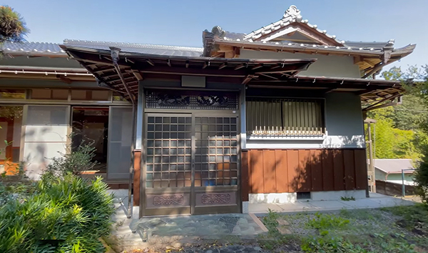 石塀に囲まれた庭園のある、入母屋の日本家屋と車庫倉庫